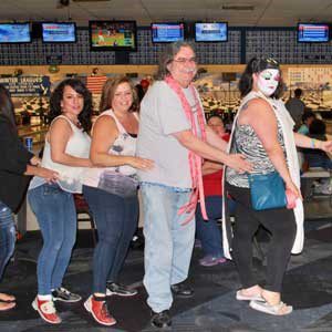 A group of people standing around in a bowling alley.